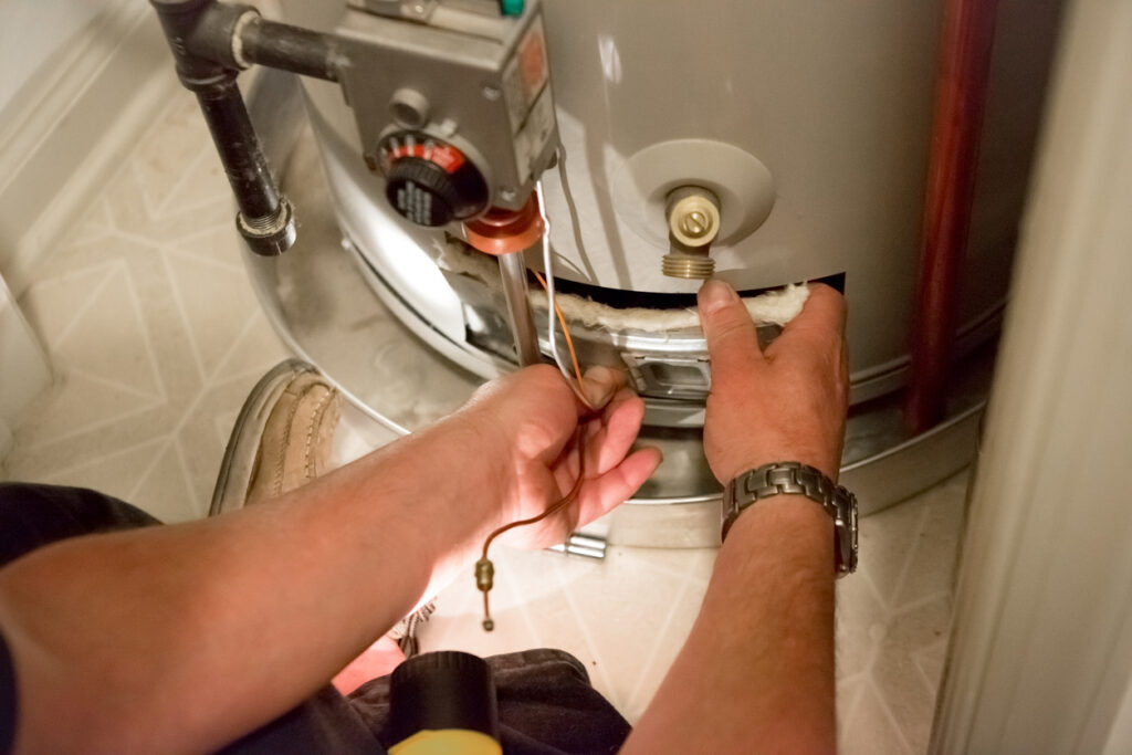 Close up of a male plumber's hands as he inspects a water heater.