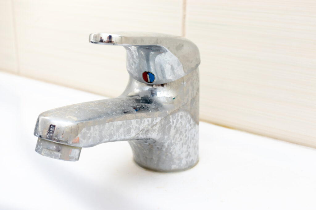 Dirty silver bathroom faucet with hard water stains